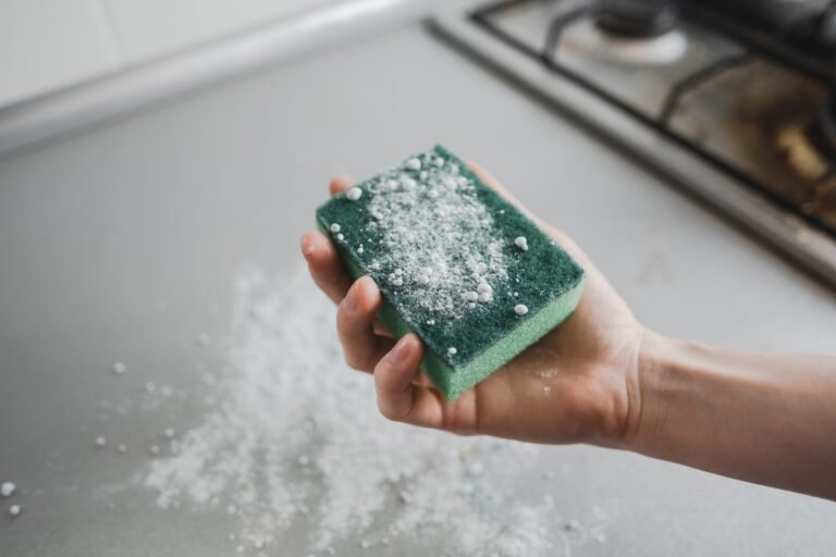 Detail cleaning a kitchen surface with a sponge and cleaning powder