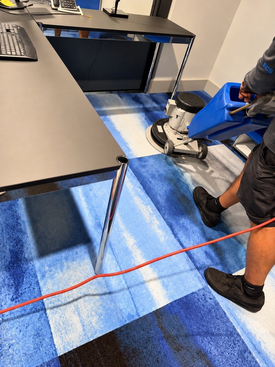 Eriko’s Cleaning team member using a rotary carpet-cleaning machine around office desks