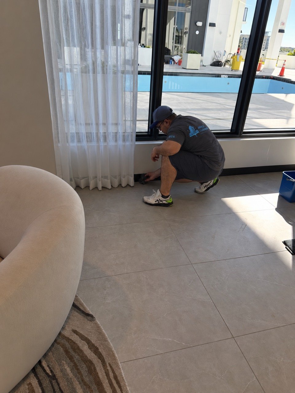 Eriko’s Cleaning team member wiping the baseboard beneath a window