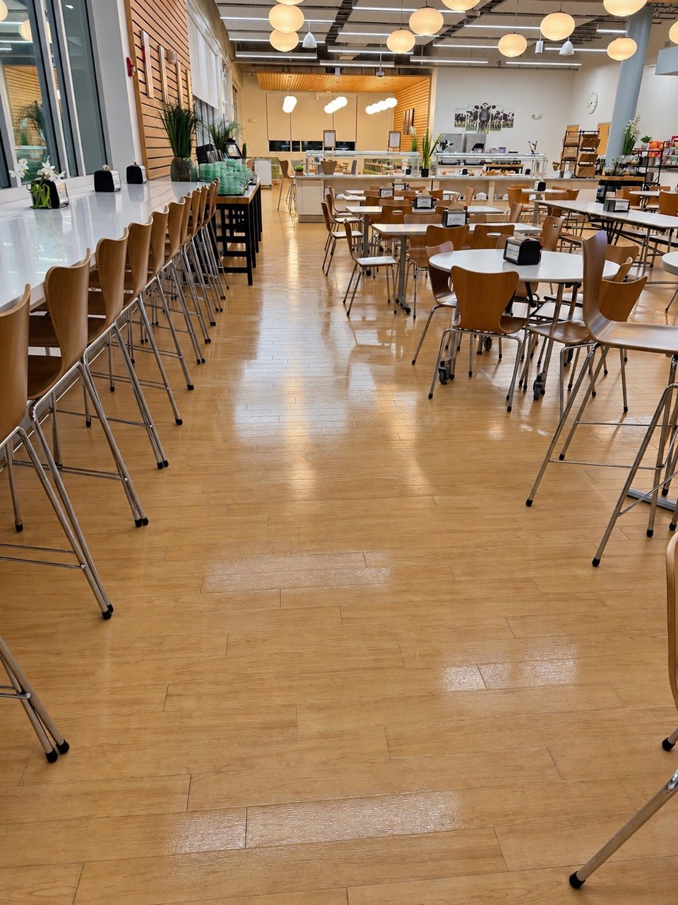 Dining area with a clean, reflective wood-look floor, tables, and bar-height seating
