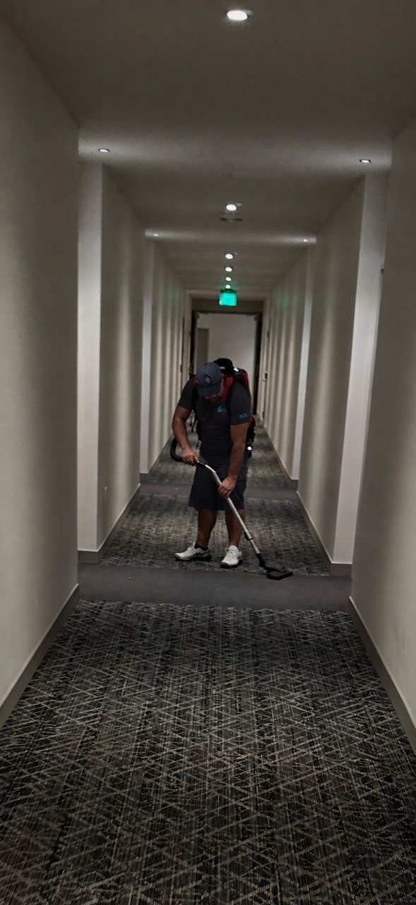 Eriko’s Cleaning team member vacuuming carpet in a commercial hallway